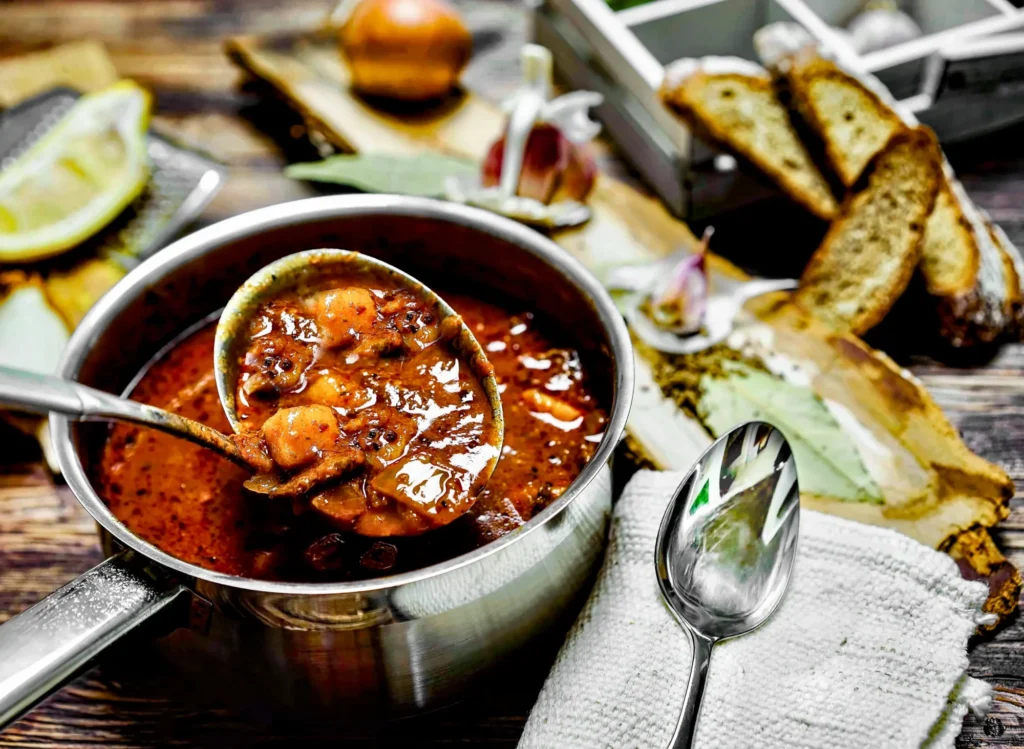 Deftige Wirtshausküche: Gulaschsuppe nach original österreichischer Art Deftige Gulaschsuppe nach original österreichischer Art serviert in einem rustikalen Topf mit Brotbeilage.
